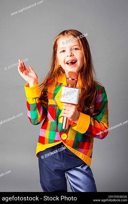 Little singer girl. Little girl with microphone over grey background. Future journalist. Future profession