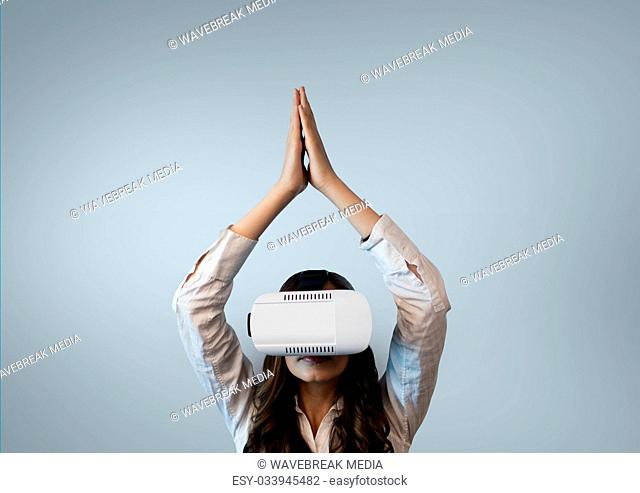 Woman in VR headset raising hands against white background
