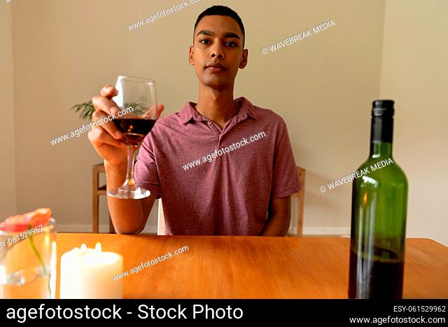 Portrait of mixed race man holding glass of red wine looking at camera