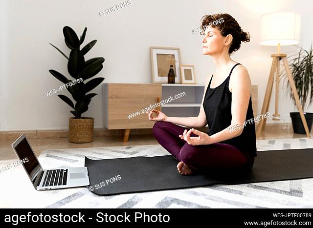 Mature woman practicing lotus position at home