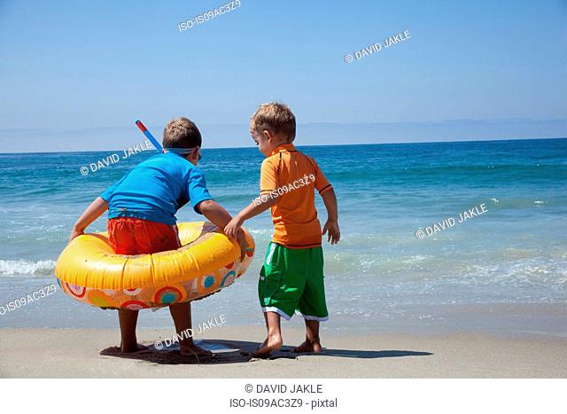 Two young brothers playing with rubber ring at beach