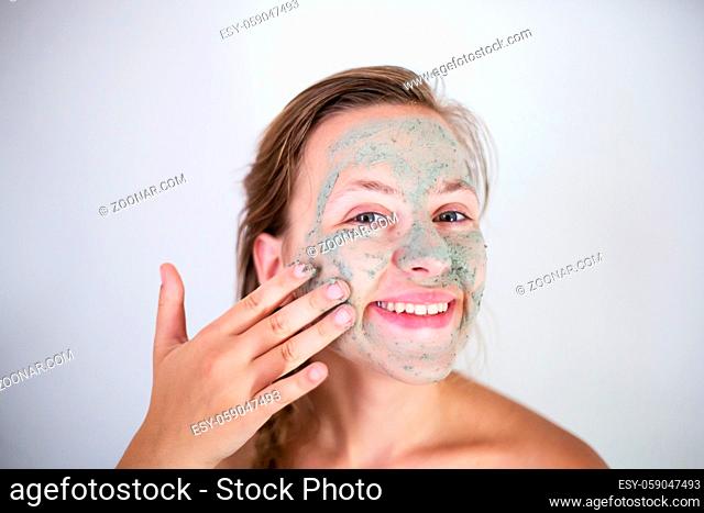 Beautifu toplessl woman with facial mask having her eyes closed. Isolated on white