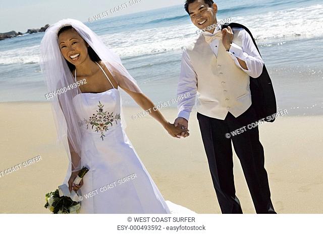 Bride and Groom holding hands on beach