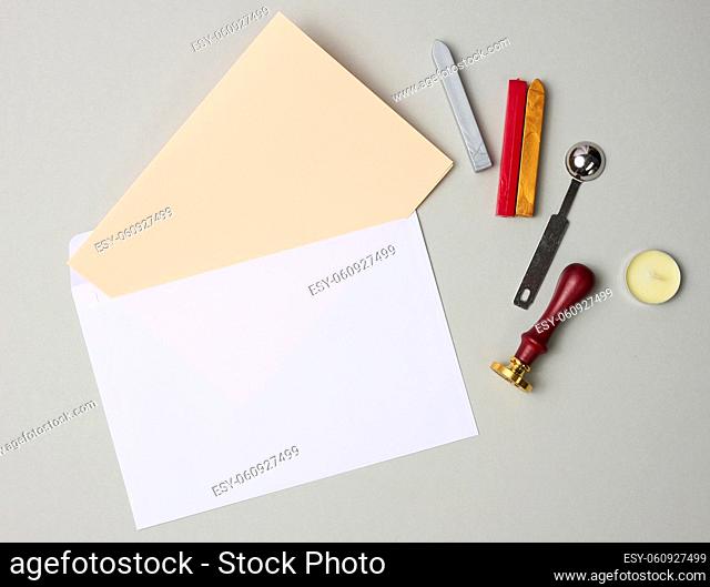 white envelope and items for sealing with wax seal on gray background, flat lay