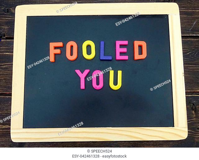 Magnetic letters on a chalkboard spelling Fooled you. April fools day concept