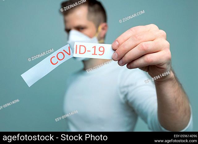 Worried man wearing a respiratory mask, holding the Coronavirus Covid-19 sign