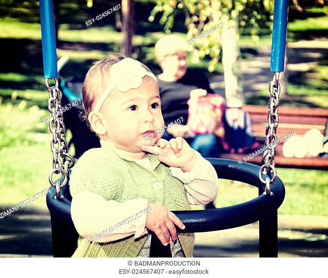 Little baby girl on the swing in park