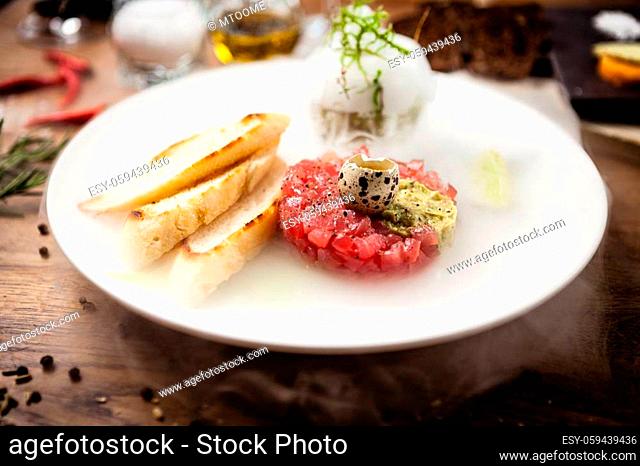 Tuna tartare: Guacamole quail egg baguette on a plate. Delicious healthy raw food closeup served for lunch on a table in modern gourmet cuisine restaurant