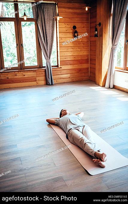 Man relaxing on yoga mat at health spa