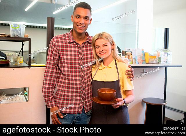 Picture of direstor of vegan restaurant or cafe and his chef loking at camera. Vegan chef woman holding plate with vegan dish