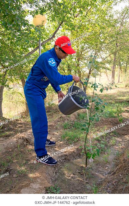 At the Cosmonaut Hotel crew quarters in Baikonur, Kazakhstan, Expedition 53-54 crewmember Joe Acaba of NASA waters a tree bearing his name he previously planted...