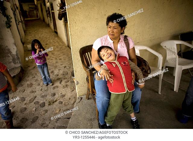 A mother holds her son who suffers infantile cerebral paralysis after his horse therapy session in Mexico City