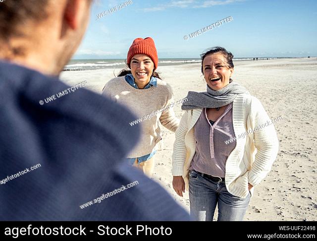 Group of friends talking and laughing at sandy beach