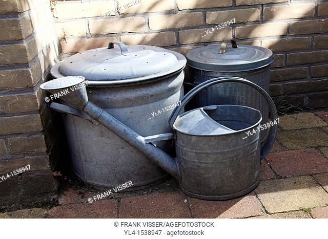 Still life of watering can and to vats in the garden. The Netherlands