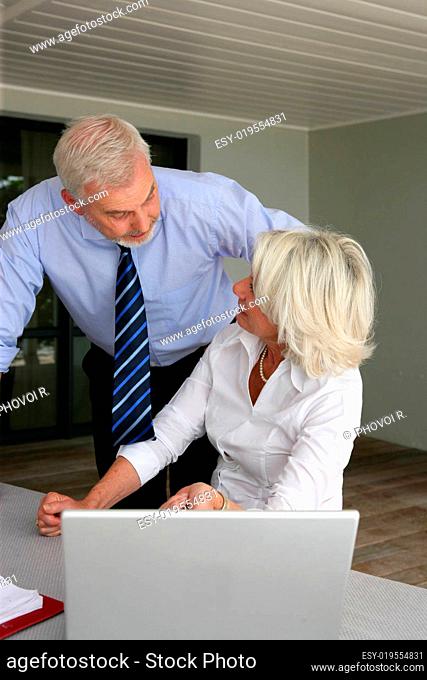 Senior man and woman looking at almost a laptop