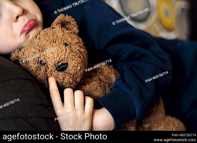 Symbolic photo on the topic of giving consolation. A little boy is sad and cuddles with his teddy bear. Berlin, March 14, 2023 || Model release available
