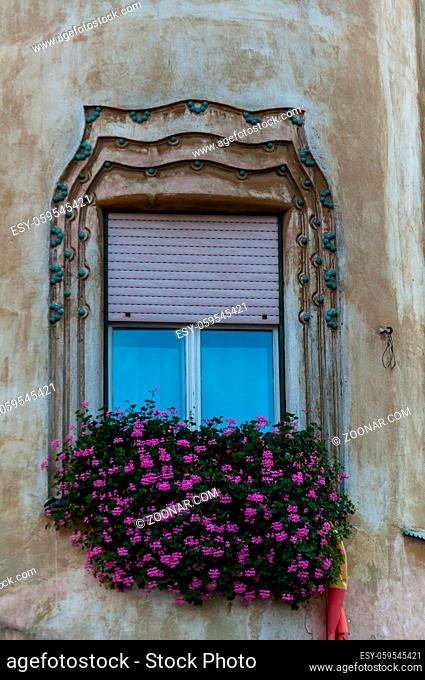 Little pink flowers decorating a window. Building facade