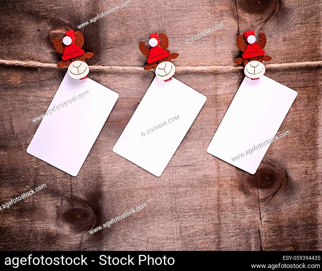 three empty paper tags hang on decorative holiday clothespins