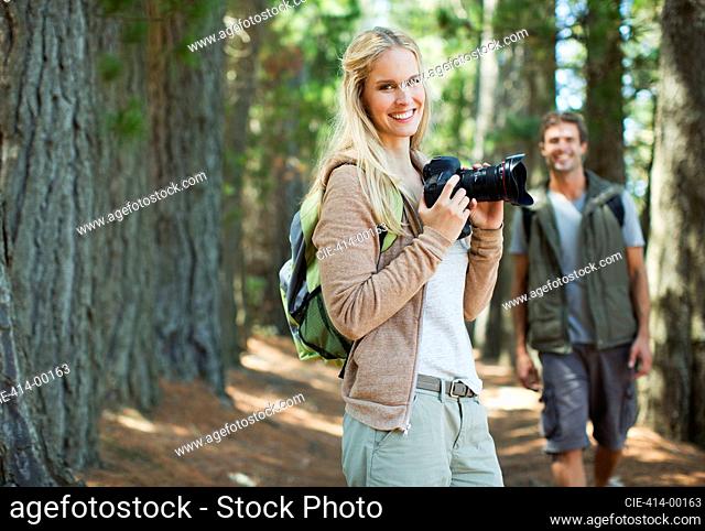 Smiling woman with digital camera in woods