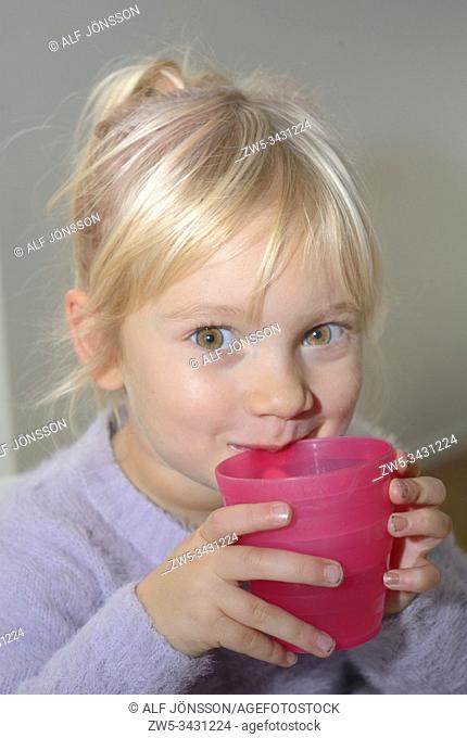 Little blond girl, 3 1/2 years old, holding a mug, looking at camera. Ystad, Sweden, Scandinavia