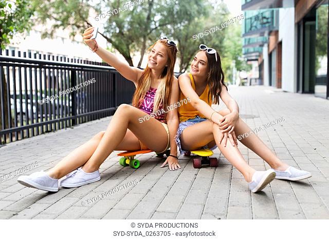 teenage girls taking selfie on city street