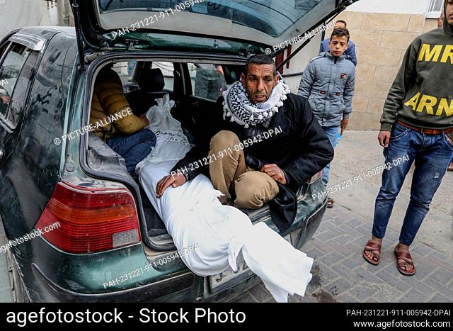 21 December 2023, Palestinian Territories, Rafah: Palestinians transport the body of a relative who was killed by Israeli airstrikes in Rafah