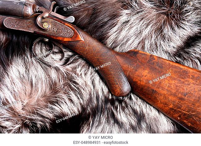 Ancient hunting shotgun on gray fur background