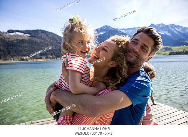 Austria, Tyrol, Walchsee, happy family hugging on a jetty at the lakeside