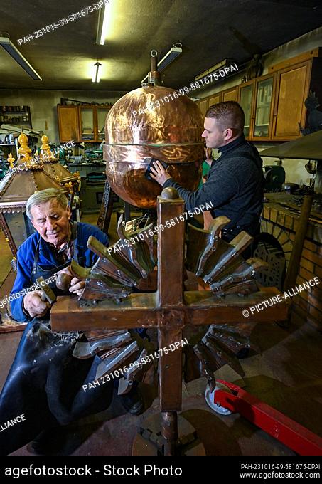 16 October 2023, Brandenburg, Angermünde: Master metalworker Wilfried Schwuchow (l) works in his workshop together with son Paul on the crowning of the...
