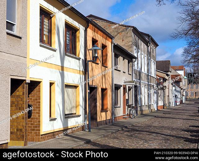 16 March 2021, Brandenburg, Perleberg: Low residential and commercial buildings stand on the cobblestone-paved Grabenstraße
