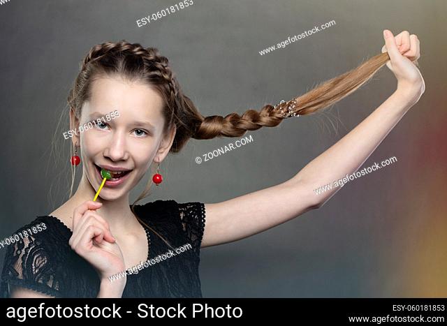A funny and mischievous teenager girl with a lollipop and a long braid