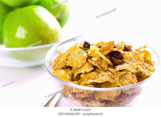 cornflakes and green apples in glass bowls on white background
