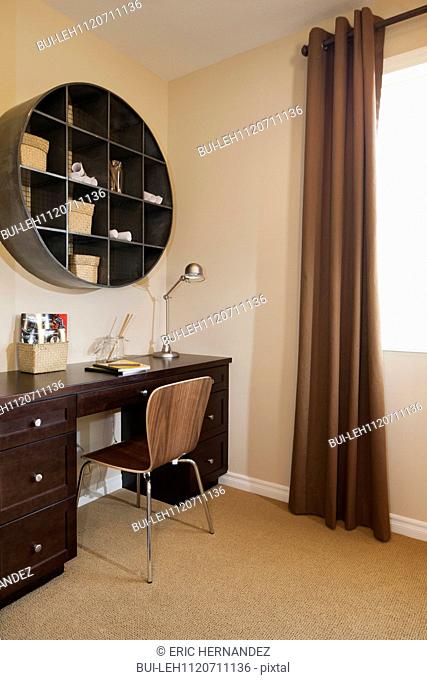 Wooden study table with circular shelves in room; Azusa; California; USA