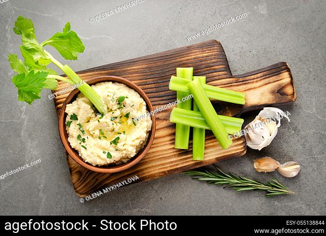 Flat lay view at vegetable Hummus dip dish topped with chickpeas and olive oil served with celery slices