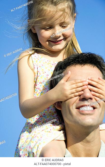 Girl covering father's eyes with her hands