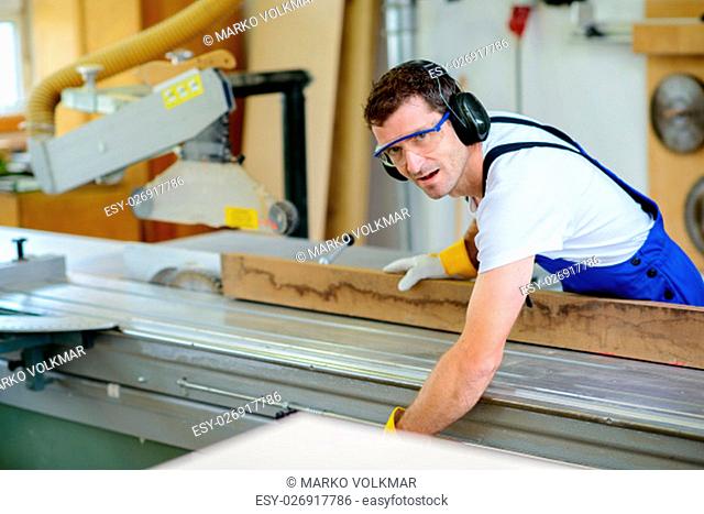 worker in a carpenter's workshop using saw machine