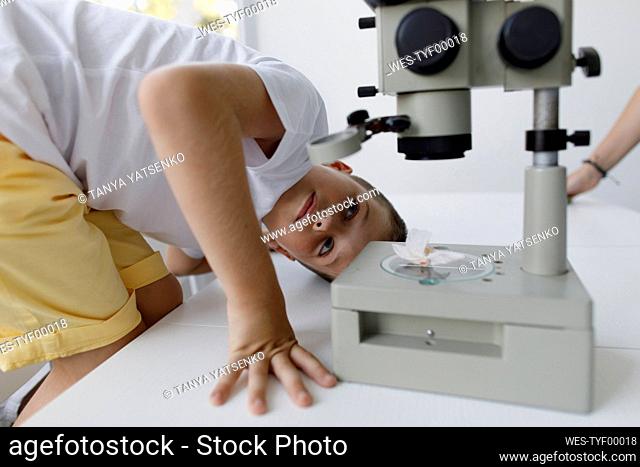 Boy looking at microscope on table