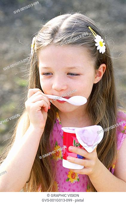 Close-up of a girl eating flavored yoghurt