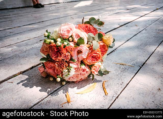 wedding bouquet of pink roses lying on wooden floor