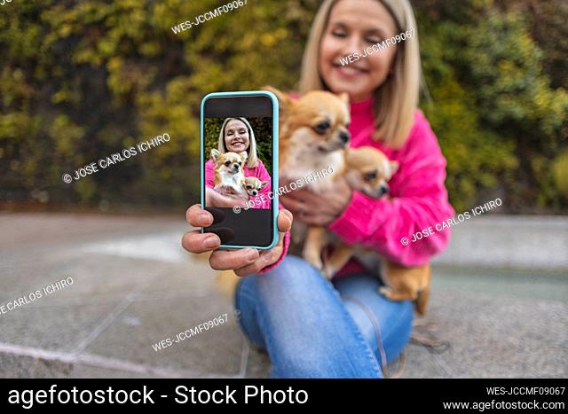 Smiling mature woman showing picture on smart phone