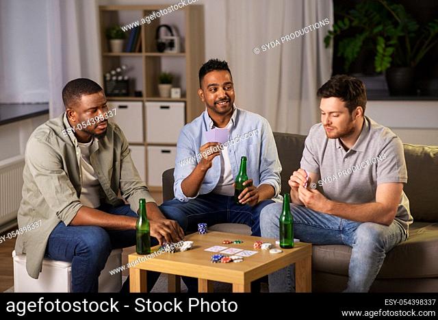 happy male friends playing cards at home at night