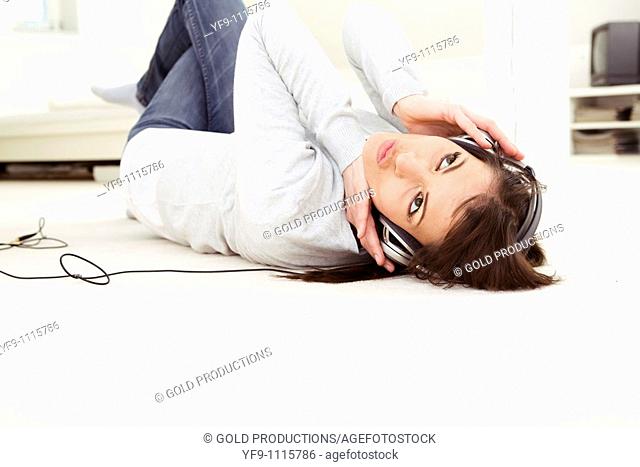 Young woman listening music lying on floor