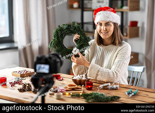 woman with camera and fir christmas wreath at home