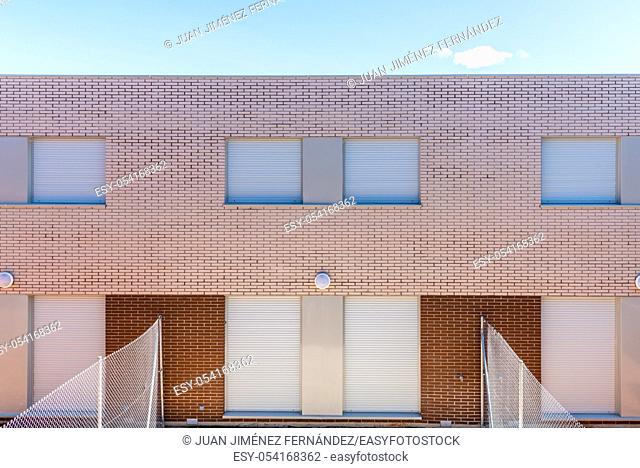 Exterior view of modern semi-detached townhouses with brick facade. Sunny day