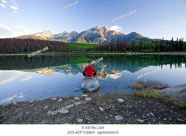 Middle age male meditating early morning at Pyramid Lake, Jasper National Park, Alberta, Canada