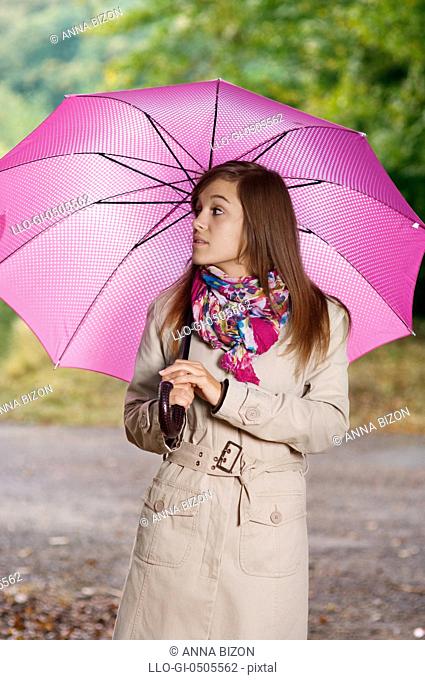 Young woman with umbrella walking through the park, Debica, Poland