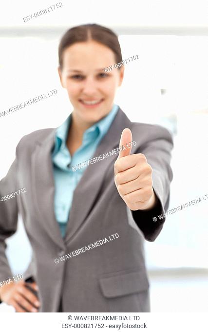 Young female executive doing a thumbs up at work