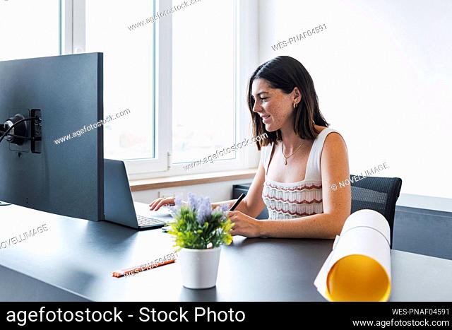 Smiling young architect working on laptop in office
