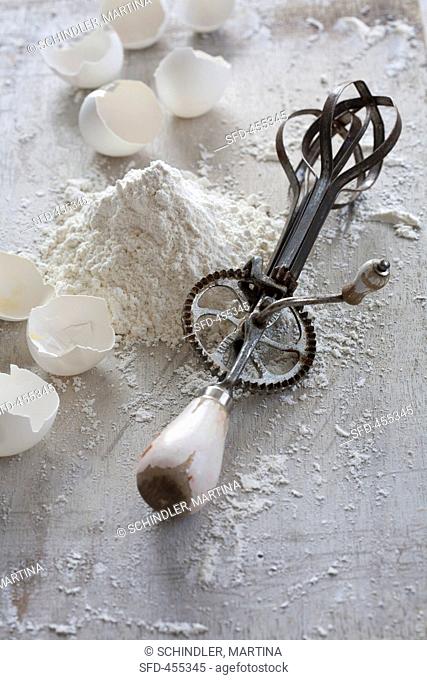 An old fashioned hand whisk with flour and egg shells