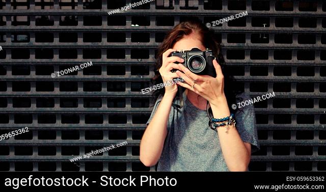 Portrait of pretty young woman with vintage camera takes photo of you, copyspace